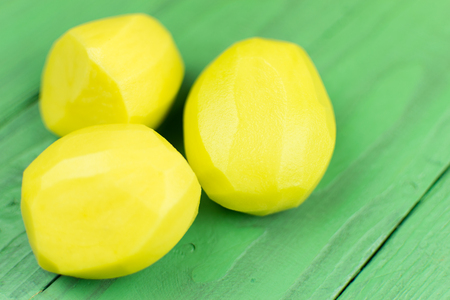Peeled potatoes on a green wooden background.の写真素材