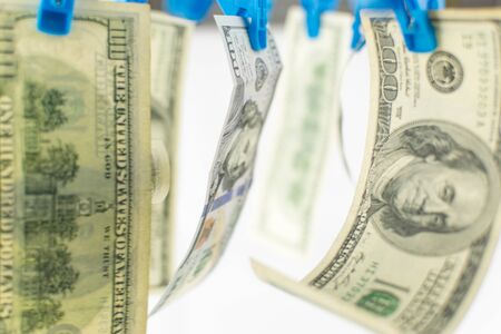 Dollar bills are dried on clothespins on a white background.の写真素材
