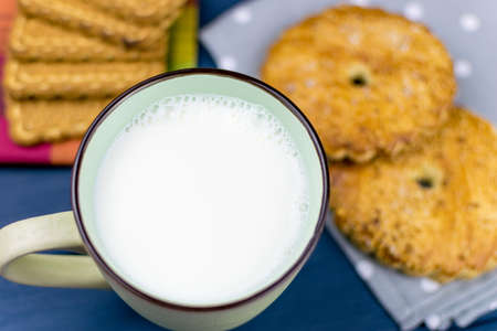 Large cup with milk and cookies in the background.の写真素材