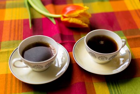 Two small cups of coffee on the saucers on the table with tulips. Meeting for two veterans: May 9 is the day of victory.の写真素材