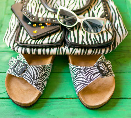 Female slaps and purse zebra coloring bag on an abstract multicolored background. The concept of travel, summer, recreation.の写真素材
