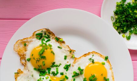 Fried chicken eggs with greens and green onions on a white plate.の写真素材
