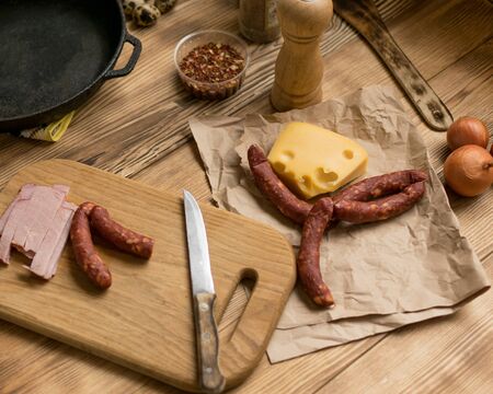 Smoked sausage, cheese on a wooden surface.の写真素材