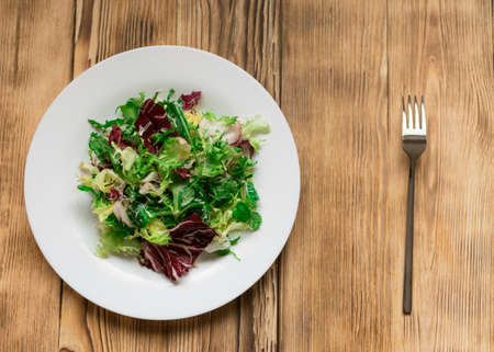 Vegetarian salad of fresh vegetables on a white plate on a wooden background.の写真素材