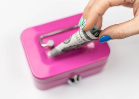 A woman's hand drops dollars into the piggy bank.の写真素材