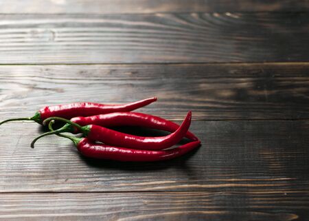 Hot chili peppers on a dark wooden background.