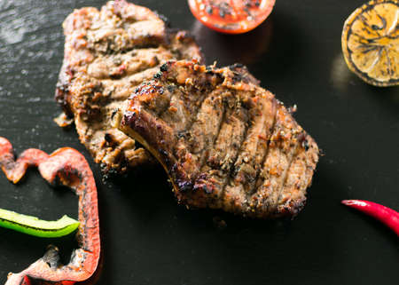 Grilled meat served with vegetables, spices on a slate plate.の写真素材