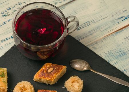 Oriental sweets and red fruit tea on black stone.