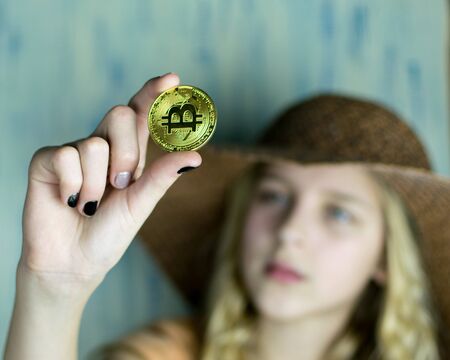 The girl is holding bitcoin on her outstretched hand.の写真素材