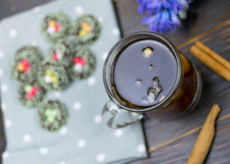 A cup with herbal tea and cookies on a dark background.