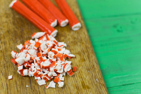 Crab sticks on cutting board on rustic wooden table on a light green wooden background.の写真素材