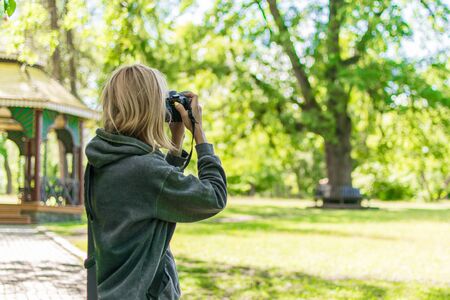 Woman photographer taking photo in a green forest in the summer.の写真素材
