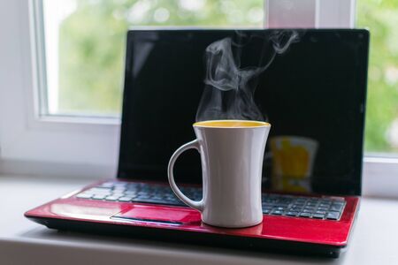 A cup of hot coffee on a laptop background.の写真素材