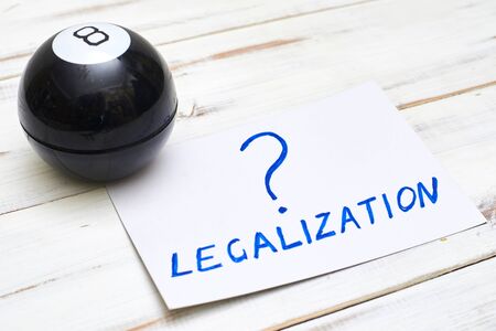 Legalization word with a question mark and a ball of predictions on a light wooden background. The concept of legal decisions taken at random.の写真素材