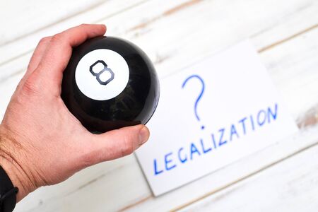 Legalization word with a question mark and a ball of predictions on a light wooden background. The concept of legal decisions taken at random.の写真素材