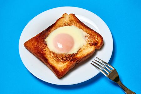 Toast with an egg on a plate on a blue background.