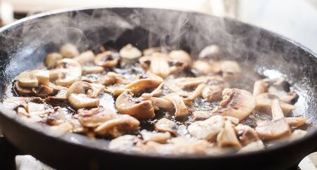 Fried mushrooms in a pan. Cooking mushrooms with steam emanating from them.の写真素材