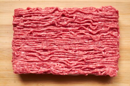 Raw minced meat on a wooden background.
