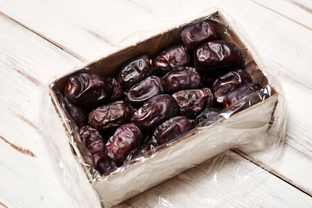 Dates lie in a box on a wooden background.の写真素材