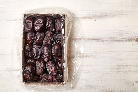 Dates lie in a box on a wooden background.の写真素材