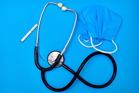 Phonendoscope and medical mask on a blue background. Medicine concept.の写真素材