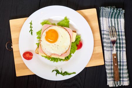 Toast with ham, egg and tomato on a plate on a black background.の写真素材