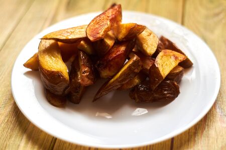 Fried crispy potatoes on a white plate on a wooden background.の写真素材