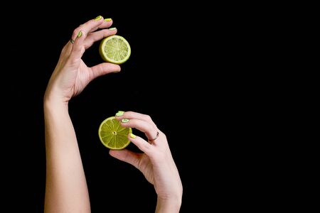 Fresh green lime in female hands on a black background.の写真素材