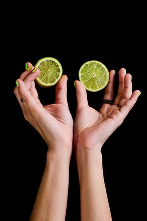 Fresh green lime in female hands on a black background.の写真素材