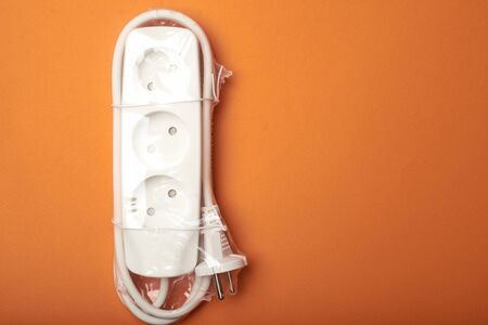Electric extension cord in packaging on an orange background.の写真素材