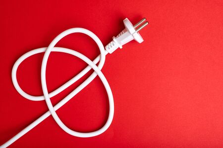Electric plug with a cord on a red background. Electrification, electricity concept.の写真素材