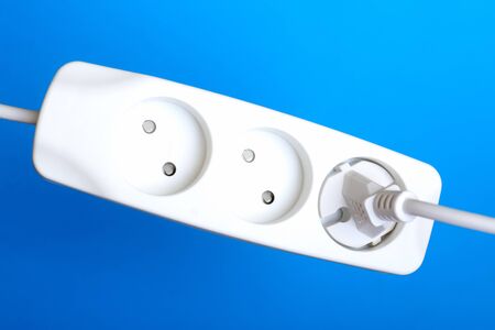 Electrical extension cord, plug and socket on a blue background. The concept of work on...