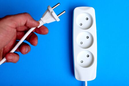 Electrical extension cord, plug and socket on a blue background. The concept of work on...