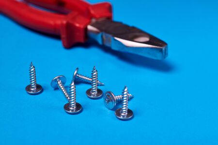 Screws and pliers on a blue background.