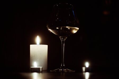 Candles and a glass of wine in the dark.