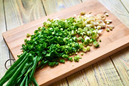chopped fresh green onions on a cutting wooden board.