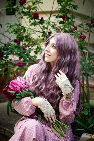 Kiev, Ukraine - June 07, 2020: Girl with long curly burgundy hair and red flowers.のeditorial素材
