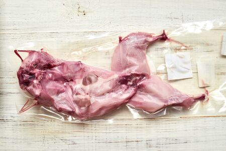 Raw rabbit in vacuum packaging on a wooden background.の写真素材