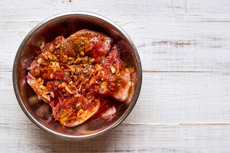 Raw rabbit in a bowl with spices. Marinate meat, preparing for cooking.