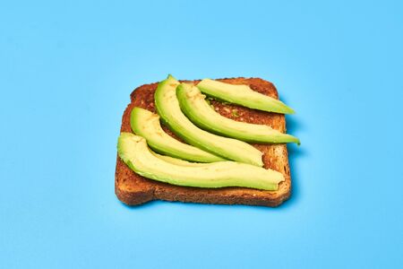 Toast with sliced avocado on a blue background.