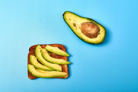 Toast with sliced avocado on a blue background.