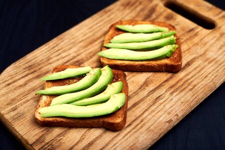 Toast with sliced avocado on a wooden background.の写真素材