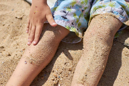 Feet of a child in the sand on the beach. The concept of carelessness and relaxation.