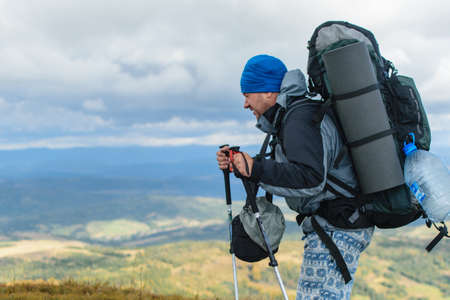 A middle-aged man with a large backpack hiking in the mountains.
