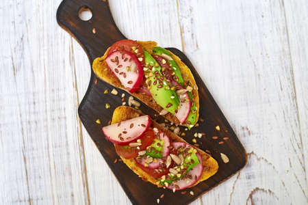 Toasts with vegetables, avocado, tomatoes, a set of seeds on a white background. Healthy food, diet concept.の写真素材