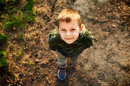 A little boy looks from the bottom up in the park.