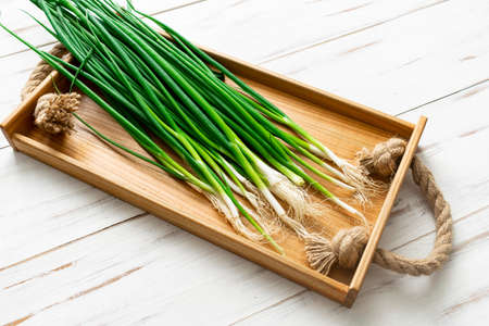 A bunch of green onions on a light wooden background.の写真素材