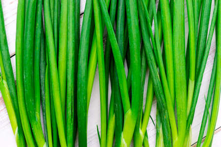 Stems of green onions on a wooden background.の写真素材