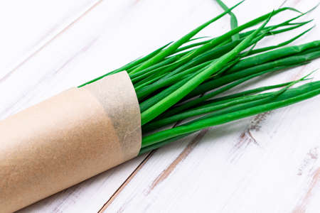 A bunch of green onions on a light wooden background.の写真素材