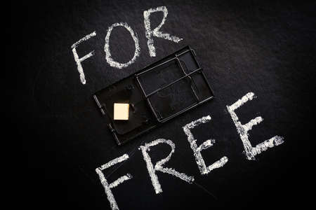 Free cheese in a mousetrap concept. Mousetrap and the inscription on a black background- For free.の写真素材